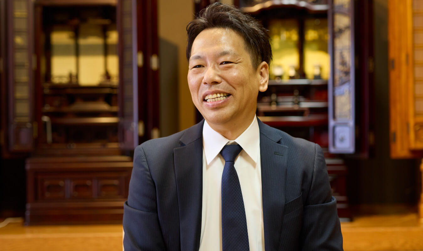 写真：現場リーダー ぬし与仏壇店 部長が笑顔で話す様子