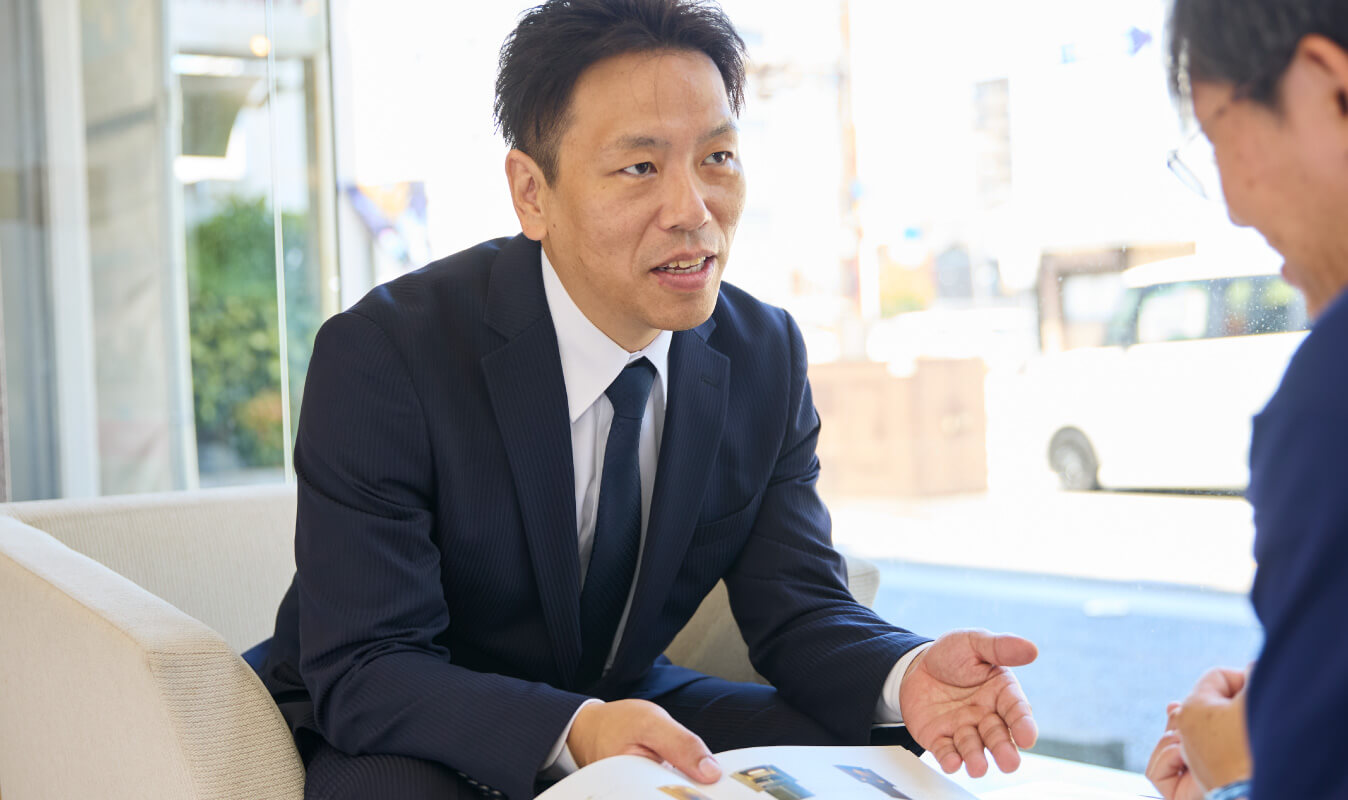 写真：現場リーダー ぬし与仏壇店 部長がカタログを手元にお客様と真剣にお話しする様子